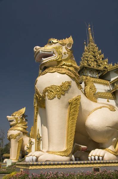 A Large White And Gold Lion Statue Sitting In Front Of A Building With