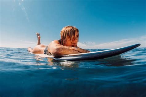 blonde surf girl riding on surfboard in ocean during surfing surfer on blue wave stock image