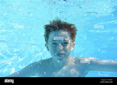 Teenage Boy Underwater In A Swimming Pool Looking Into Camera Stock