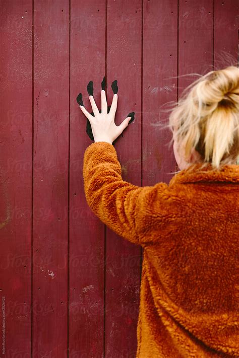 Female Preteen With Her Hand Over A Black Handprint On A Wooden Door