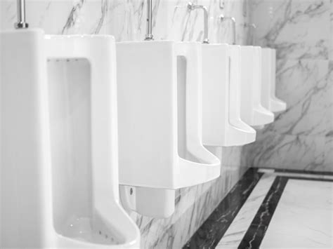 fila de urinóis de cerâmica branca limpa na parede de mármore no banheiro público masculino