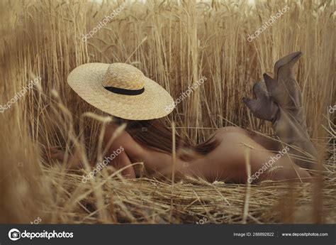 Mujer desnuda acostada en un campo con sombrero fotografía de stock antgor