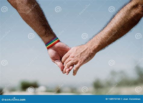 closeup of a gay couple holding hands rainbow flag is a symbol of lesbian gay bisexual and