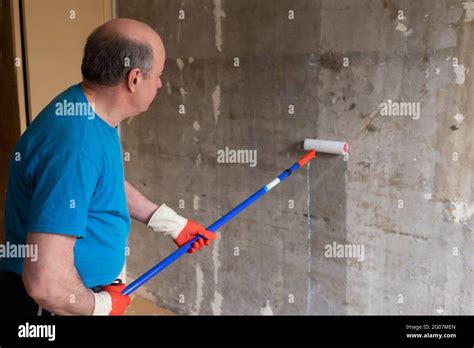 Man Painting Cement Walls Using Roller Brush And Primer Making A