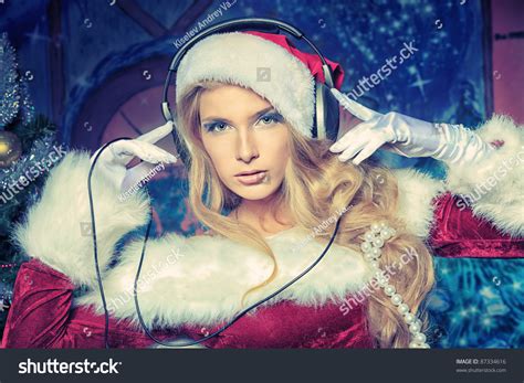 Beautiful Young Woman In Santa Claus Clothes And Headphones Over Christmas Background Stock