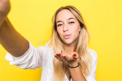 Pretty Woman Making Selfie And Sends Air Kiss At The Camera Over Yellow