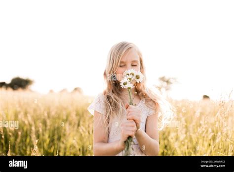 Cute Girl Smelling Daisy Flowers In Field Stock Photo Alamy