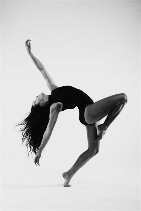Black And White Photograph Of A Woman Doing A Handstand On One Leg With Her Arms In The Air