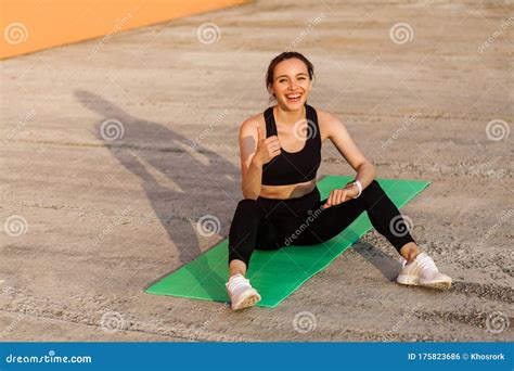 Delighted Athletic Girl In Black Pants And Top Smiling And Showing