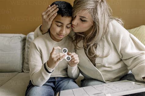 Mother Kissing Son While Teaching At Home Stock Photo