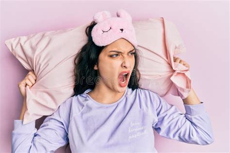 beautiful middle eastern woman wearing sleep mask and pajama sleeping on pillow angry and mad