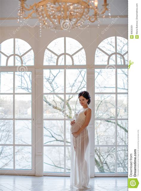 Portrait Of A Girl Pregnant Brunette In A White Transparent Dress In