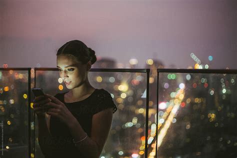 Woman Checking Her Smartphone On A Rooftop Bar By Stocksy Contributor Jovo Jovanovic Stocksy