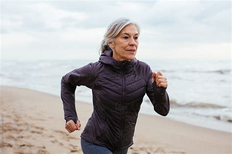 Active Senior Woman Running On The Beach By Stocksy Contributor