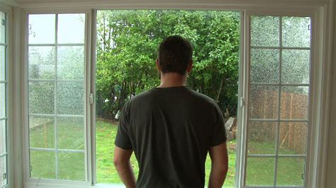 Man Watching The Rain Come Down Through Window Stock Video Footage