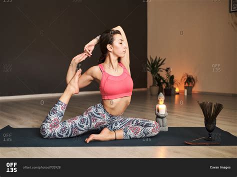 Young Woman Doing Yoga On Yoga Mat In Atmospheric Yoga Studio Stock