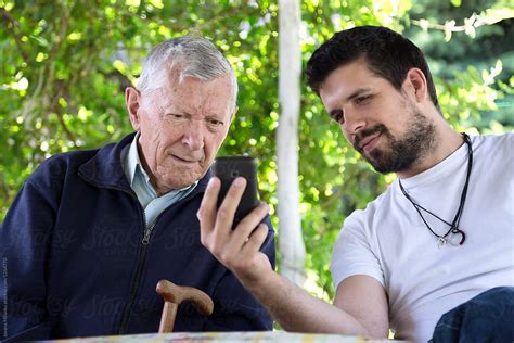 Grandson Teaching His Grandfather To Use Touchscreen Mobile Phone Del
