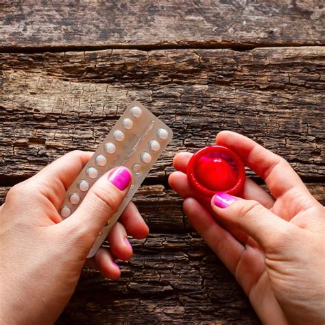 Premium Photo Young Woman Holding A Birth Control Pills And A Condom