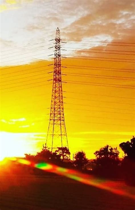 The Sun Is Setting Behind An Electric Tower