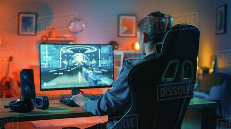Back Shot Of A Gamer Playing First Person Shooter Online Video Game On His Powerful Personal
