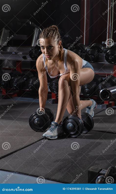 Woman In The Gym Back And Shoulders Exersises With Dumbbells Stock