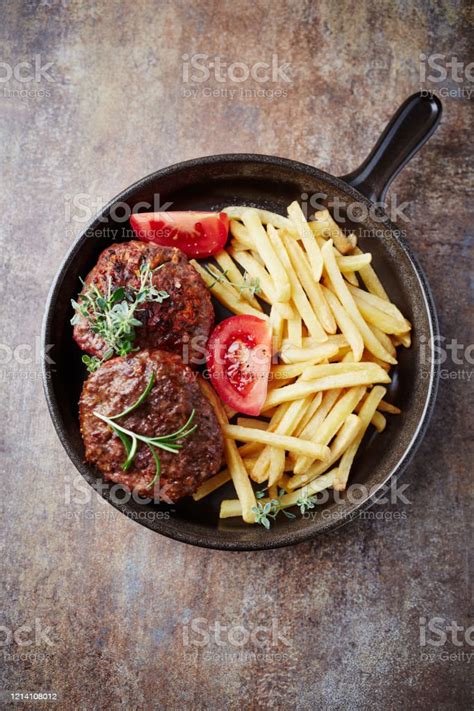 Fried Hamburger Steaks With Tomatoes And French Fries Rustic Background