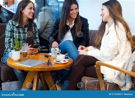 Three Young Woman Drinking Coffee And Speaking At Cafe Shop Stock
