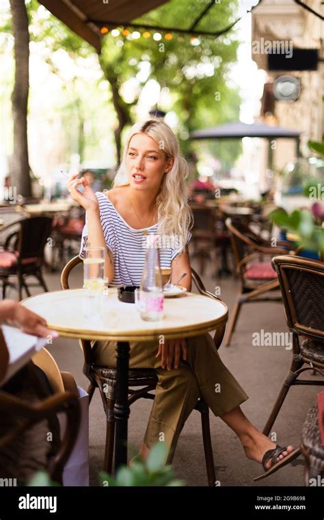 Young Woman Smoking A Cigarette And Drinking Coffee While Sitting