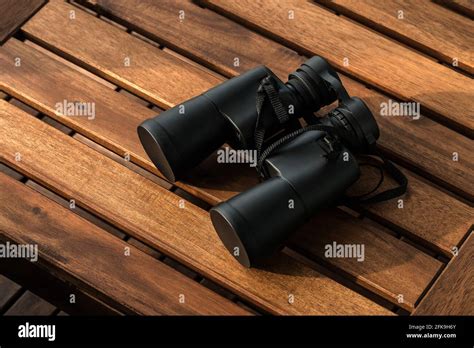Black Binoculars On A Brown Wooden Table Background With Copy Space