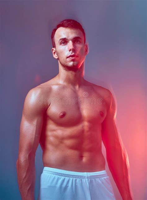 athletic male with naked muscular torso posing in colorful light sports man shows trained abs