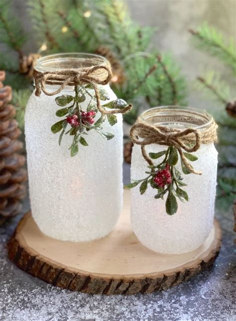 Two Mason Jars Decorated With Holly And Berries Are Sitting On A Piece