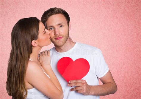 Romantic Woman Kissing On The Cheek Of Man Holding A Heart Shape Stock Image Image Of Brown