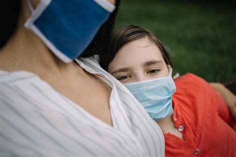 Girl With Antivirus Mask Sitting In Her Mother S Arms Stock Image