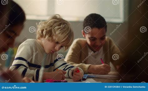 Children Sitting At Round Table In Classroom Students Drawing In