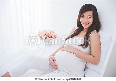 Beautiful Pregnant Asian Woman Leaning On A Bed Smiling A Portrait Of A Beautiful Asian