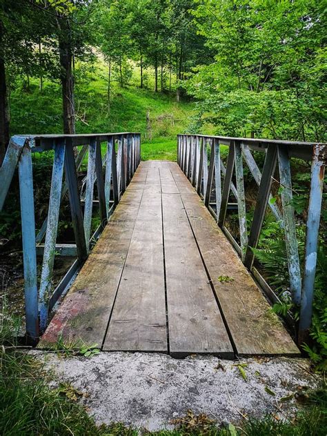 Small Wooden Bridge With Metal Railings Over Small River Stock Photo