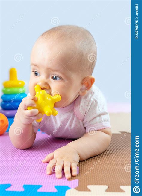 A Newborn Baby Chews On A Yellow Silicone Toy Teething In Babies Stock