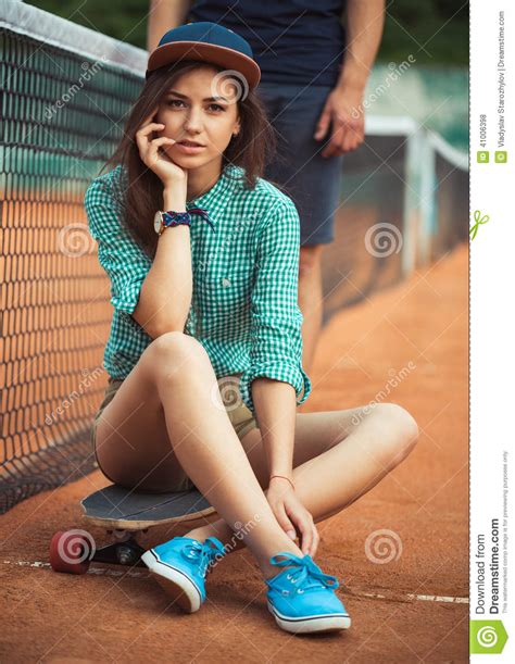 Girl Sitting On A Skateboard On The Tennis Court Stock