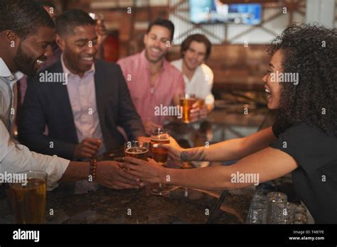 Barmaid Serving Group Of Male Friends On Night Out For Bachelor Party