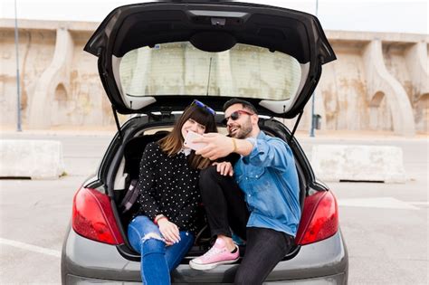 Heureux Jeune Couple Assis Dans Le Coffre De Voiture Prenant