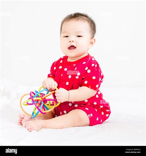 Portrait Of A Little Adorable Infant Baby Girl Sitting On The Bed And
