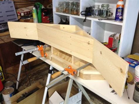 An Unfinished Boat Is Being Built In A Workshop With Tools On The Table