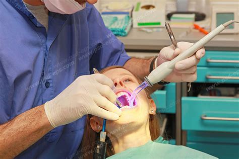 عکس با کیفیت تبلیغاتی پزشک در حال انجام کار روی دندان های بیمار روی صندلی دندانپزشکی لایه باز