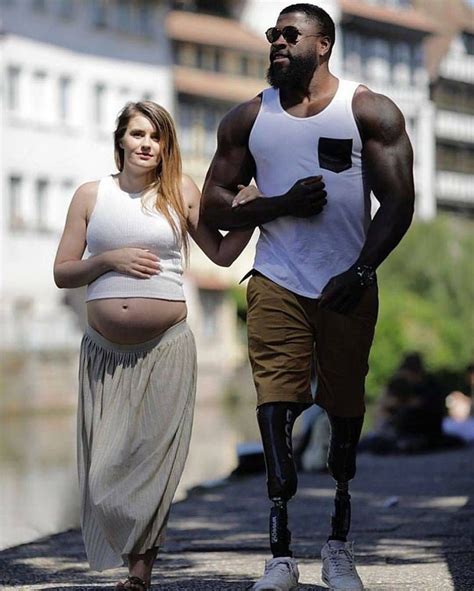 A Pregnant Woman Walking Next To A Man In White Tank Top And Tan Skirt With Black Leggings