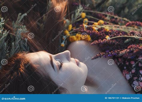 Close Up Face Of Beautiful Girl Lying On The Grass With Bouquet Of