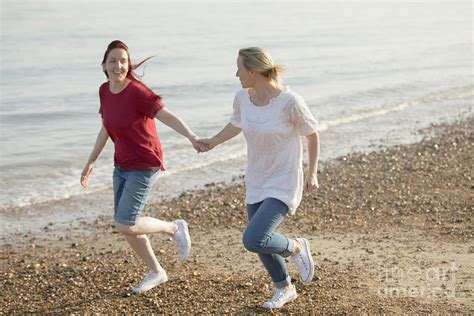Playful Lesbian Couple Holding Hands And Running Photograph By Caia Imagescience Photo Library