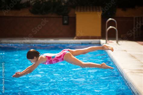 Young Girl Jumping Head First Into The Pool In Summer Stock Foto