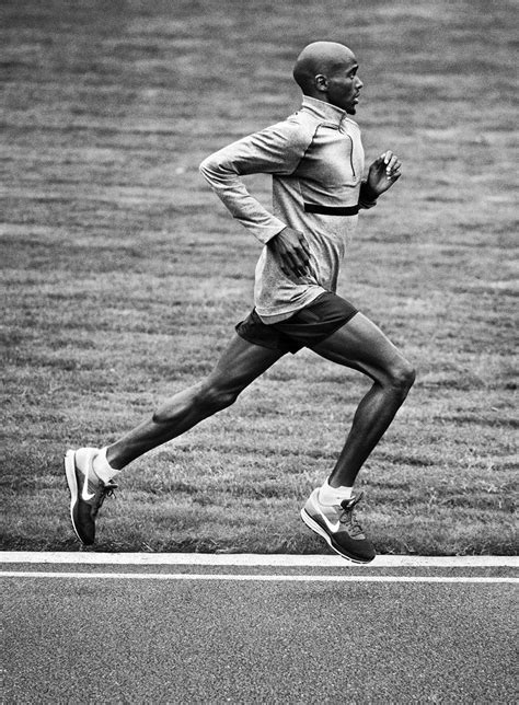A Man Is Running On The Grass In A Black And White Photo With His Head
