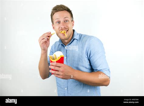 Young Handsome Man Eats French Fries From Fast Food Restaurant Looks