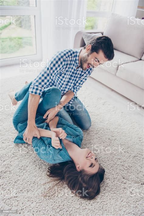 Excited Young Couple Is Fooling Around And Plays Indoors At Home At A